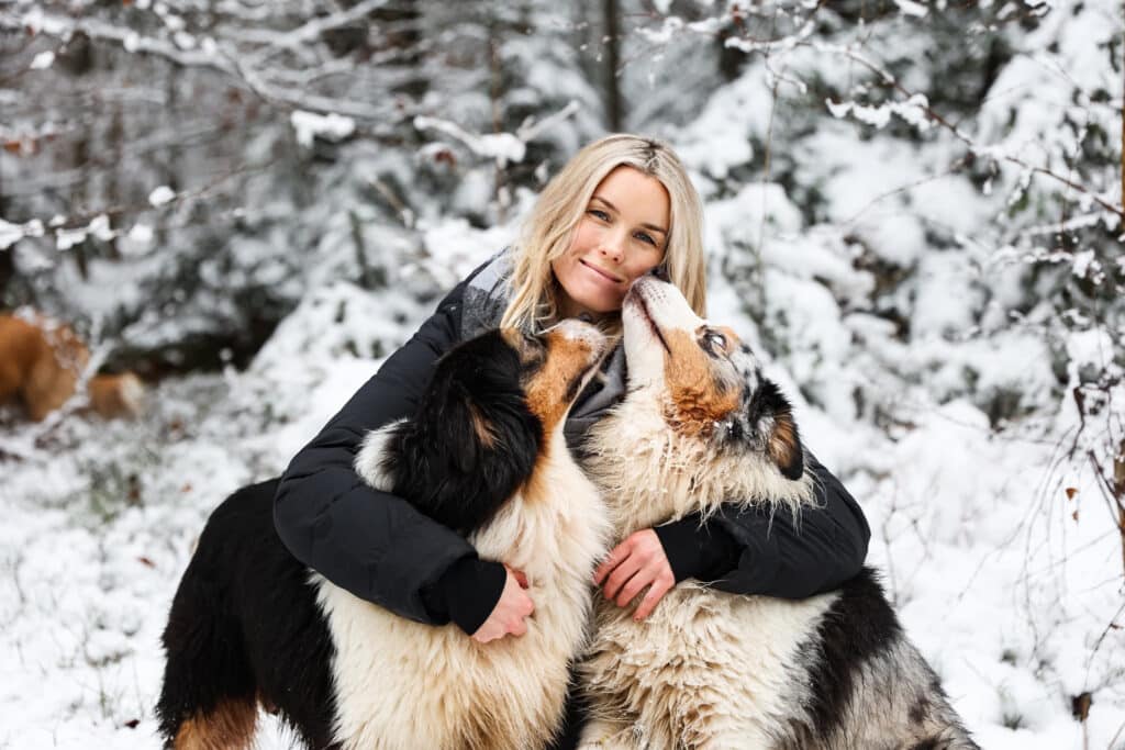 Melanie mit zwei Ihrer Australian Shepherds im Schnee. So schön kann Hundeliebe sein.