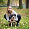 Young woman playing with Australian Shepherd dog outdoors in the